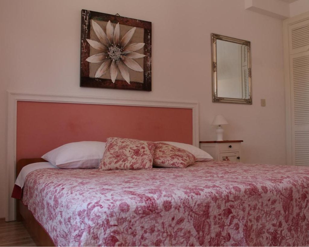 Apartment 1 bedroom with a rose-coloured headboard and floral quilt