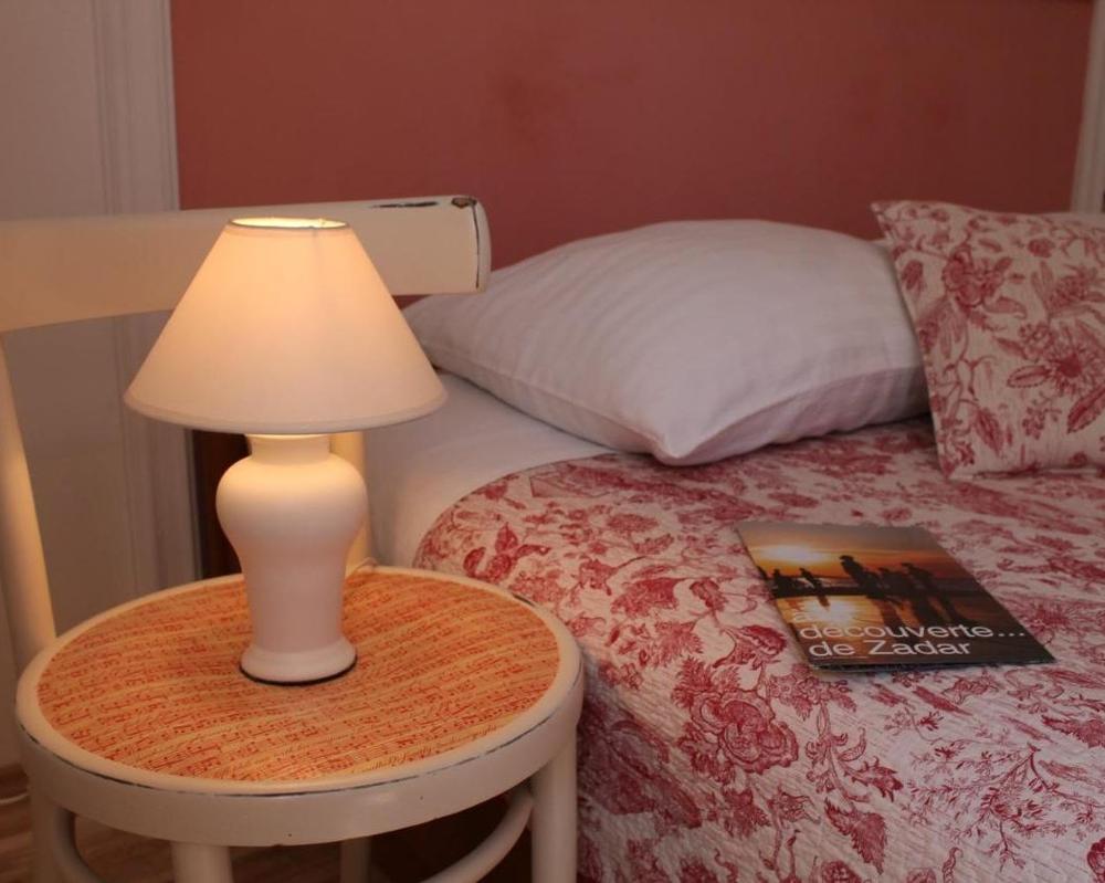 Bedside lamp beside the rose-coloured headboard