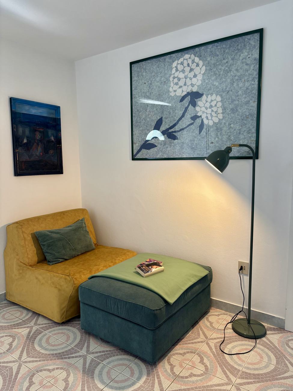 The lounge corner with a mustard sofa bed and reading lamp