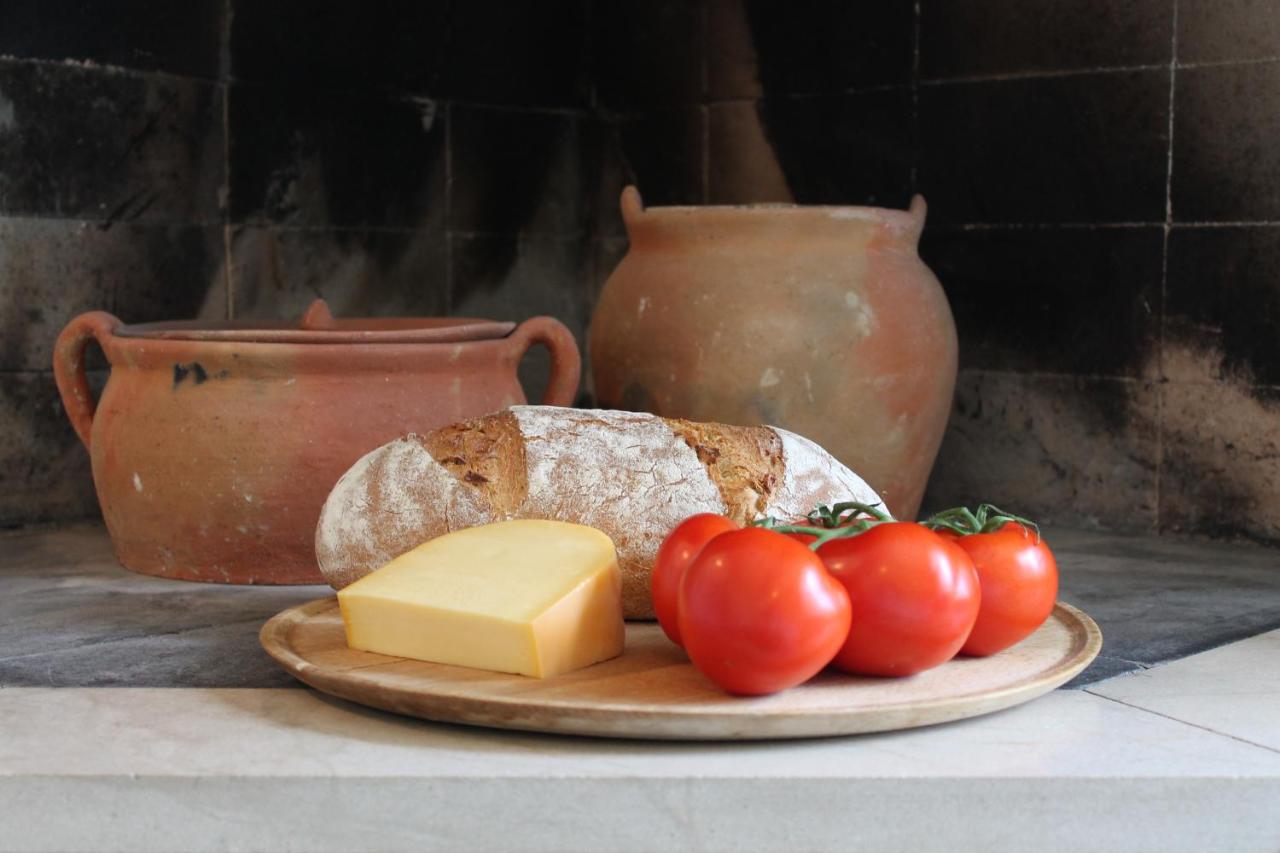 Bread, cheese and tomatoes on a wooden board before an old stone hearth